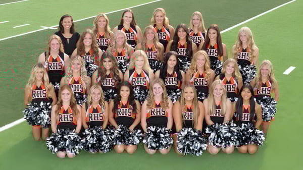 Las porristas de la Rockford High School posan en uniformes uniformes en un campo deportivo verde.