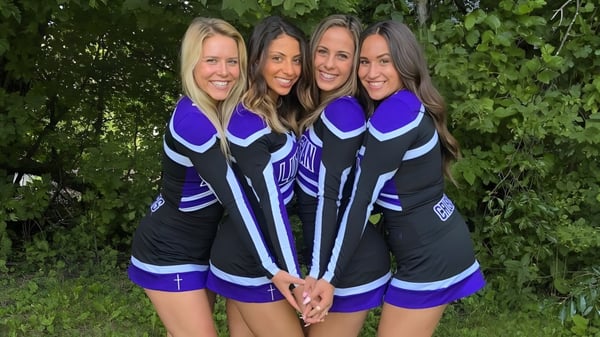 Cuatro estudiantes de la Rockford Lutheran School están juntas en uniformes deportivos en el área exterior verde.