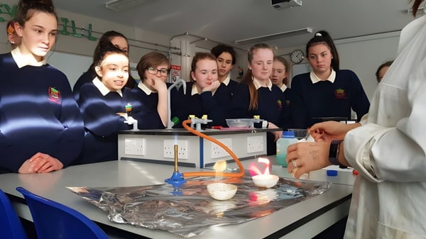 Alumnos de la Rockford Manor School observan juntos un experimento con equipos de laboratorio en la mesa de clase.