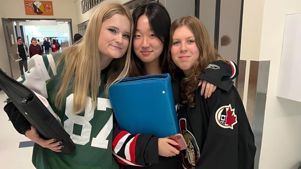 Tres estudiantes de la Rockland District High School están juntas en el pasillo y se abrazan.