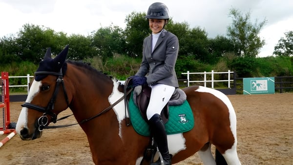 Una persona en equipo de equitación monta un caballo marrón en la zona exterior de la Rockport School.