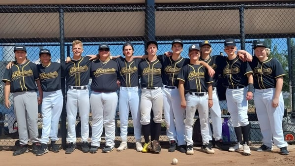 Un grupo de estudiantes que juegan al béisbol está en el campo de béisbol de la Rockwell Charter School.