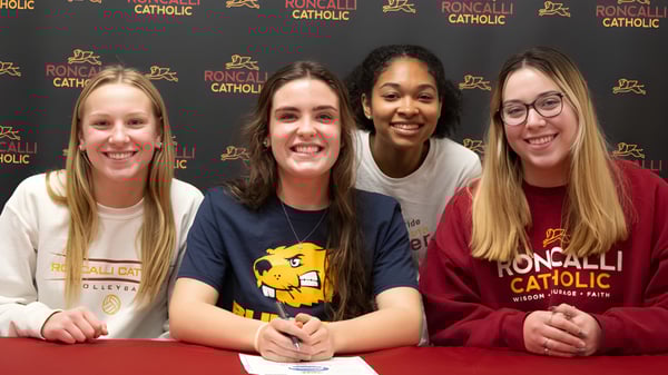 Cuatro estudiantes posan juntas frente a un logo de Roncalli Catholic High School.