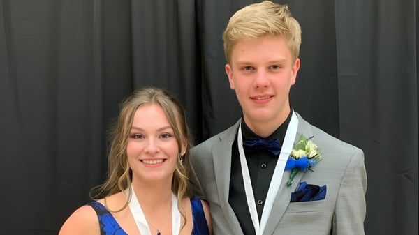 Una pareja vestida formalmente está frente a una cortina oscura en el campus de la Roncalli Central High.