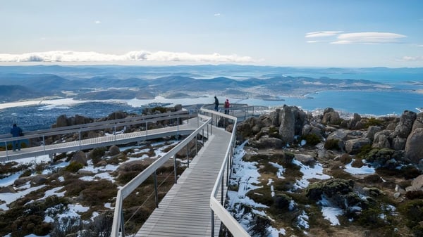 Alumnos de Rosny College caminan por un sendero de madera a través de un paisaje montano cubierto de nieve hacia un mirador.