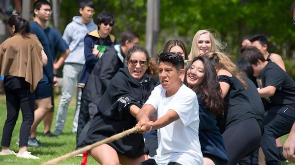 Un grupo de estudiantes está reunido al aire libre en un prado en el campus de la Ross School.