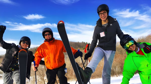 Un grupo de estudiantes de la Ross School está de pie bajo un cielo despejado en un campo cubierto de nieve con ropa de invierno.