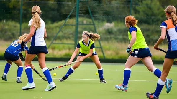 Alumnas de la Rossall School juegan hockey sobre césped en un campo de césped artificial rodeado de árboles.