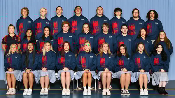 Un grupo de alumnas en uniformes idénticos posan frente a una pared azul en el campus de la Roxby Downs Area School.