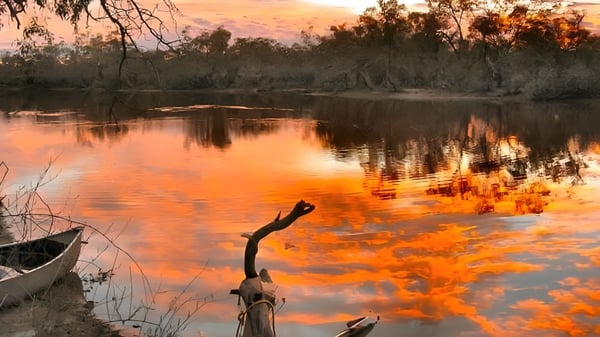 Un lago tranquilo con un atardecer otoñal y vegetación circundante en el terreno de la Roxby Downs Area School.