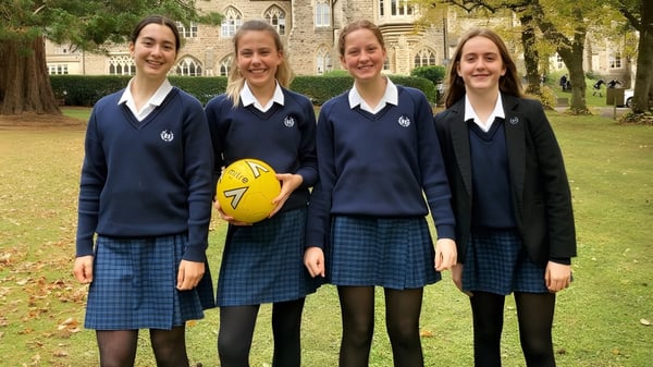 Cuatro alumnas en uniformes escolares están juntas en el campus de la Royal High School en el área verde.