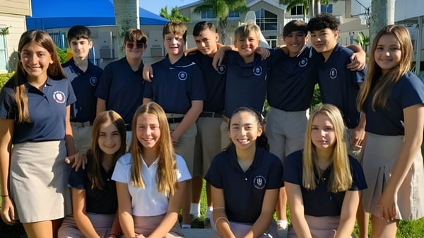 Un grupo de estudiantes de la Royal Palm Academy posa juntos frente a un edificio con palmeras de fondo.