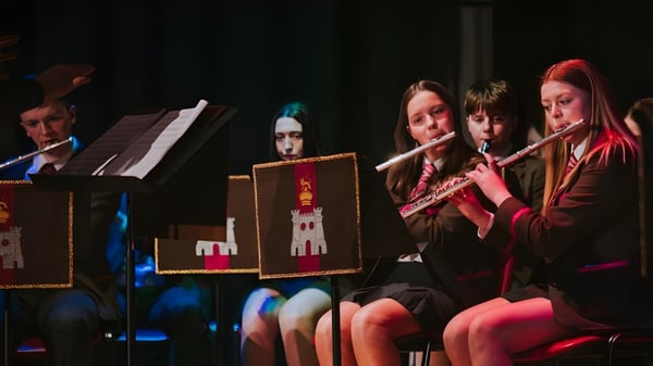 Un grupo de músicos de la Royal School Dungannon toca juntos varios instrumentos en el escenario.