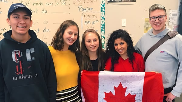 Estudiantes de la Rutland Senior Secondary School sostienen juntos la bandera canadiense en un aula.