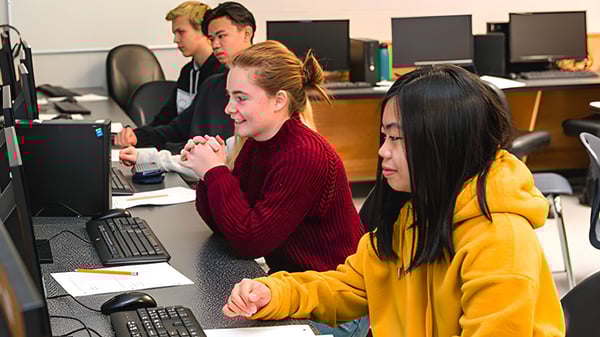 Un grupo de alumnas y alumnos de la Sa-Hali Secondary School están sentados en el aula de computación y trabajando en computadoras.