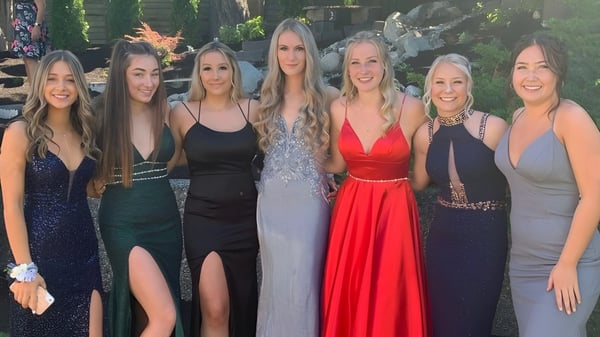 Un grupo de seis alumnas de la Sa-Hali Secondary School posan al aire libre frente a una construcción de madera y vegetación verde.