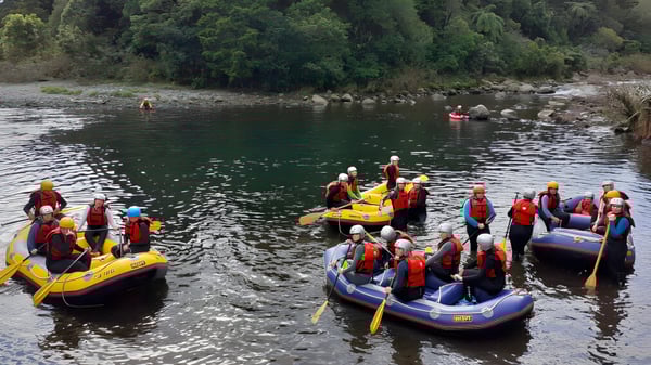 Estudiantes del Sacred Heart Girls' College en New Plymouth haciendo rafting en un río con un entorno verde.