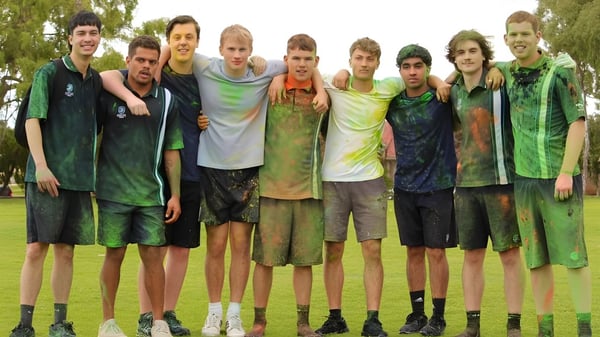 Un grupo de estudiantes está de pie en un campo al aire libre en el terreno de la Safety Bay Senior High School.