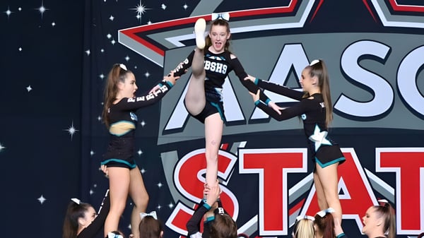 Estudiantes de la Safety Bay Senior High School realizan una actuación de danza en el escenario con el gran logo de ASC STAT de fondo.