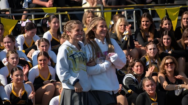 Un grupo de estudiantes se encuentra afuera frente a un fondo amarillo en el campus de Saint Anthony's High School.