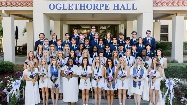 Un gran grupo de alumnas en togas blancas celebra la graduación frente al Oglethorpe Hall en el campus de la Saint Edward's School.