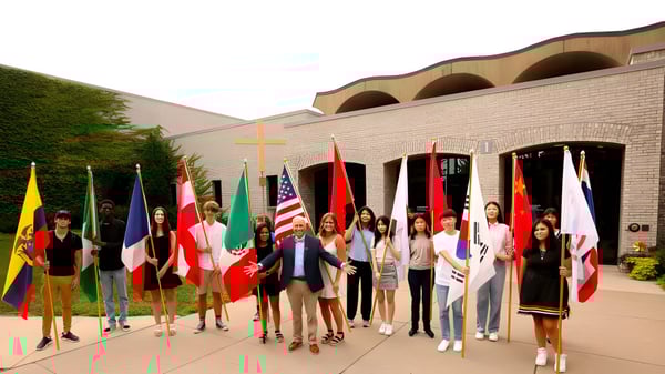 Un grupo de personas con banderas nacionales está frente a un edificio en el campus de Saint John‘s Prep.