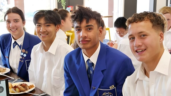 Estudiantes del Saint Kentigern College están sentados juntos en una mesa y comiendo en la mensa de la escuela.