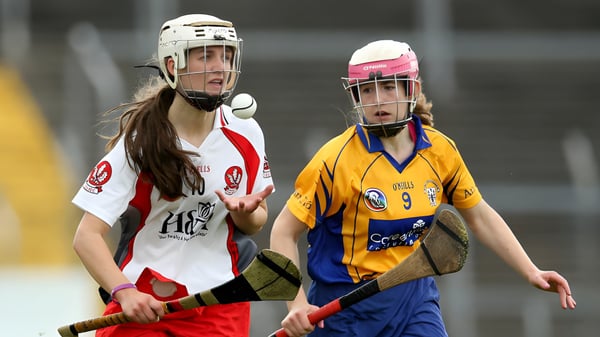 Dos alumnas de la Salerno Secondary School están en uniformes de hockey en el campo de hockey de una arena deportiva.