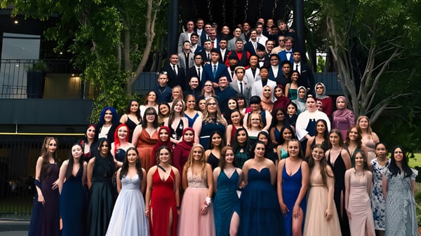 Un grupo de estudiantes de la Salisbury High School se reúne al aire libre frente a un fondo verde.