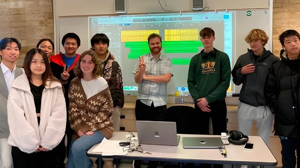 Estudiantes de la San Domenico School trabajan juntos en laptops en un aula con una pantalla grande.