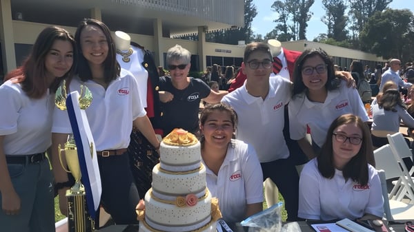 Estudiantes de la San Luis Obispo High School celebran juntos al aire libre con un gran pastel.