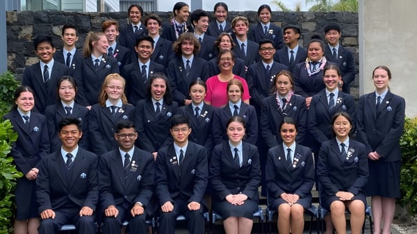 Un gran grupo de alumnos en uniformes escolares se reúne en el área exterior del campus del Sancta Maria College.