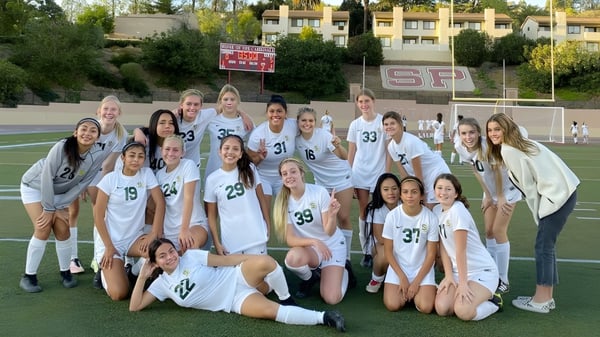 Un grupo de jugadoras de fútbol de la Santa Barbara High School posan juntas en el campo de fútbol.
