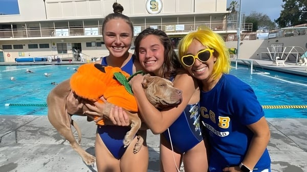 Tres mujeres posan sonriendo frente a una piscina en el terreno del Santa Barbara Unified School District.