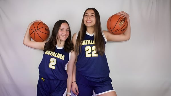 Dos alumnas de la Santa Catalina School posan con balones de baloncesto frente a un fondo blanco.