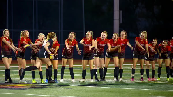 Un grupo de jugadoras de fútbol en camisetas rojas está en el campo de la Santiam Christian School.