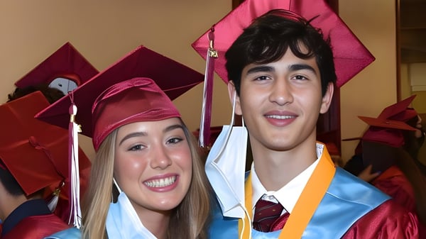Dos graduados de la Scecina Memorial High School posan juntos en la ceremonia de graduación con togas.
