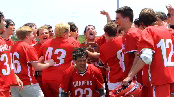 Un grupo de estudiantes del Schull Community College en camisetas rojas celebra juntos durante un partido.