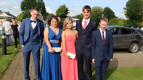 Un grupo de personas está de pie en un camino en el área verde del campus de Scoil Aireagail.