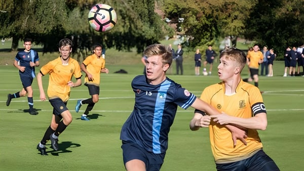 Alumnos de Scoil Dara juegan un partido de fútbol en un campo cubierto de hierba.
