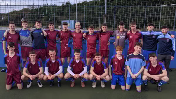 Un grupo de jugadores de fútbol masculinos posan en el campo de la Scoil Mhuire gan Smál con camisetas rojas y azules.