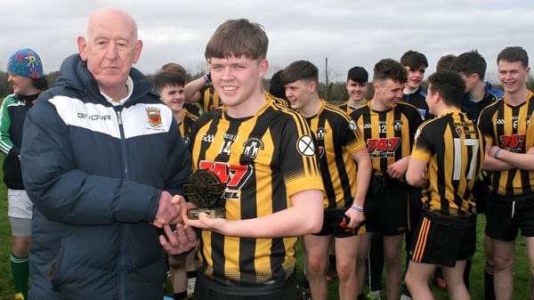 Un grupo de jóvenes futbolistas de Scoil Mhuire (Strokestown) está con su entrenador en el campo de fútbol.