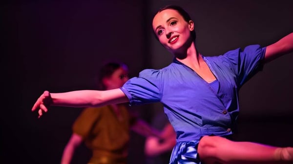 Una mujer vestida de azul baila en el escenario de la Scoil Ruáin.