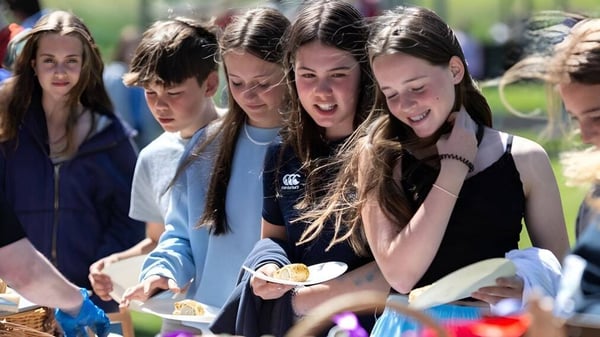 Un grupo de estudiantes de la Scoil Ruáin conversa riendo al aire libre en el recinto escolar.