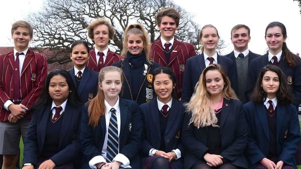 Un grupo de estudiantes en uniformes escolares está frente a árboles desnudos en el terreno de Scotch Oakburn College.