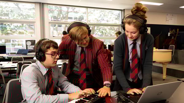 Estudiantes del Scots College trabajan juntos en una laptop en un aula con vista al exterior.