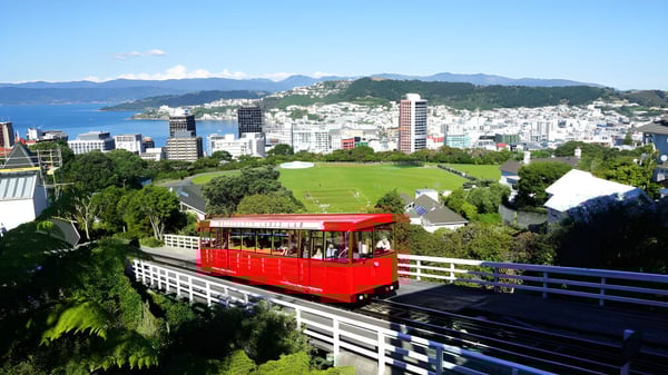 Un teleférico rojo ofrece en el terreno del Scots College una vista panorámica de la ciudad con rascacielos y montañas de fondo.