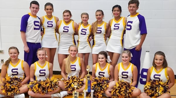 Un grupo de animadoras de la Scottsburg High School posa frente a una pared blanca.