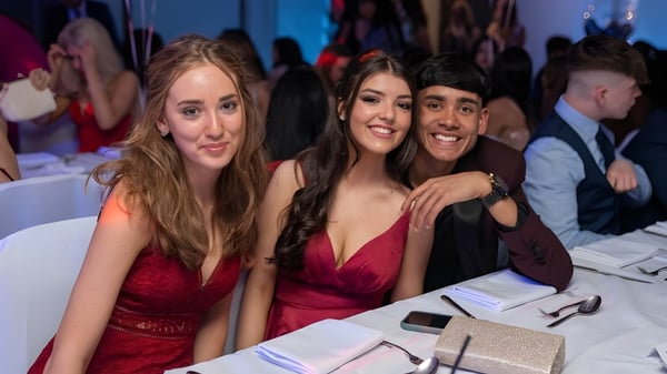Tres estudiantes del Seaford College vestidas de forma elegante posan juntas en una celebración.