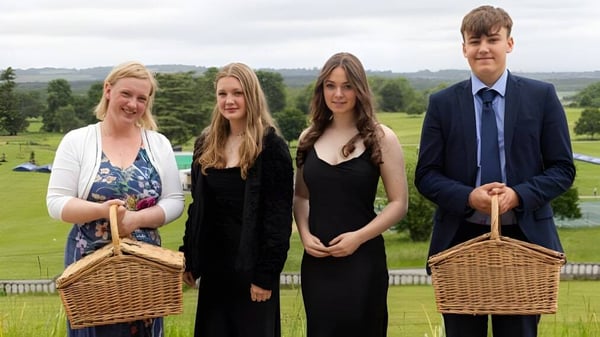 Un grupo de cuatro personas con cestas está en el terreno del Seaford College frente a un prado con árboles.